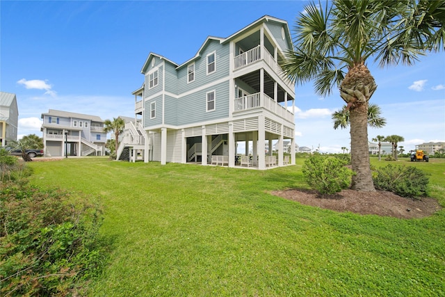 26711 Bay Water Dr, Galveston, TX 77554 - rear view of house with stairs, a balcony, and a yard