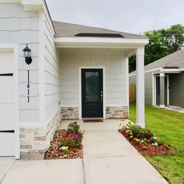 11411 Bright Sun Dr, Houston, TX 77048 - view of exterior entry featuring a yard, roof with shingles, and stone siding