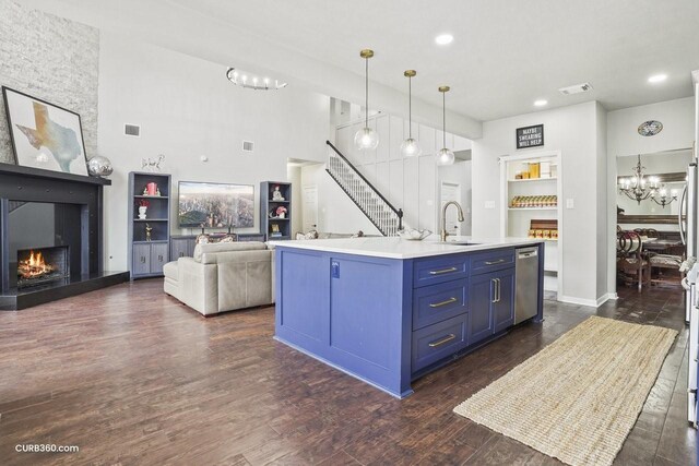 kitchen featuring a sink, a chandelier, a large fireplace, stainless steel dishwasher, and blue cabinets