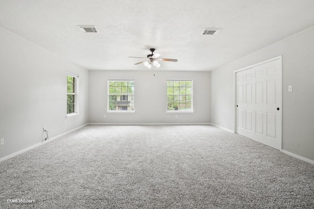 spare room featuring visible vents, ceiling fan, carpet floors, and a textured ceiling