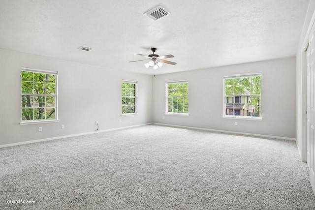 carpeted spare room with a textured ceiling, a ceiling fan, and visible vents