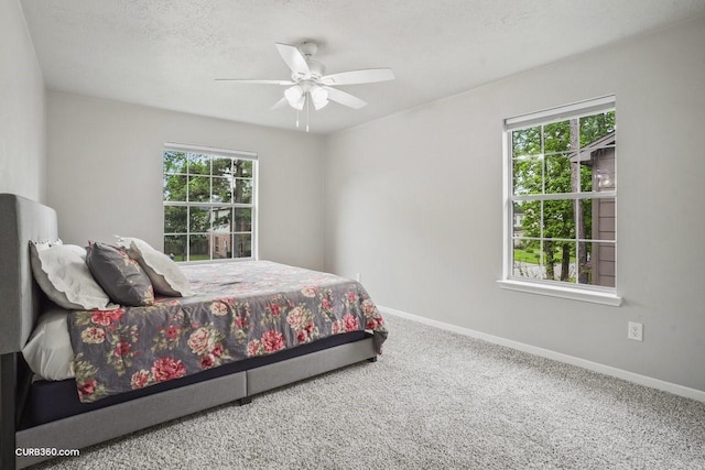 carpeted bedroom featuring baseboards, a ceiling fan, and a textured ceiling