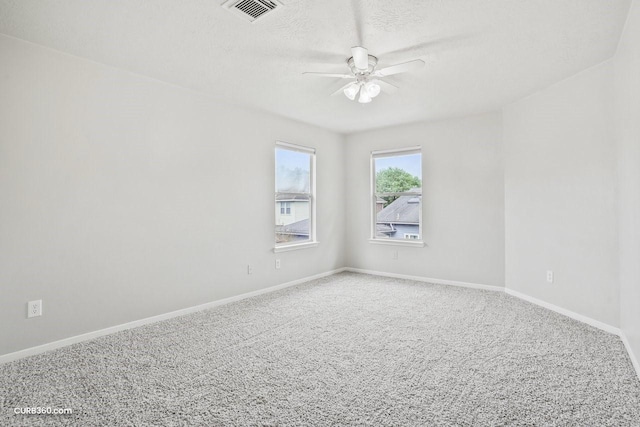 spare room with baseboards, carpet flooring, a textured ceiling, visible vents, and ceiling fan