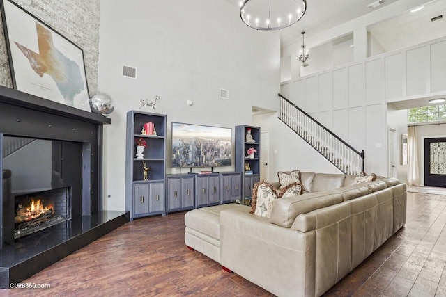 living room featuring visible vents, stairway, wood finished floors, and a lit fireplace
