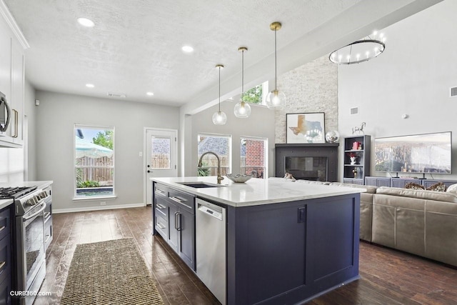 kitchen with open floor plan, a textured ceiling, dark wood-type flooring, appliances with stainless steel finishes, and a sink