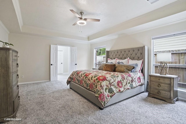 carpeted bedroom featuring a raised ceiling, crown molding, ceiling fan, and baseboards