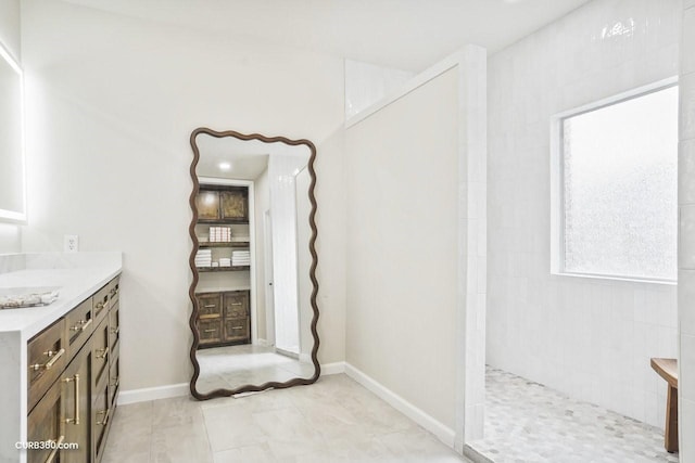 full bathroom with vanity, baseboards, and walk in shower