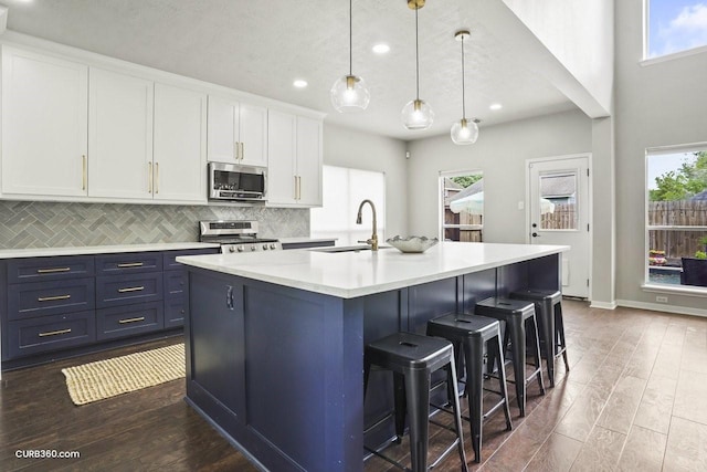 kitchen with a sink, backsplash, appliances with stainless steel finishes, and dark wood-type flooring