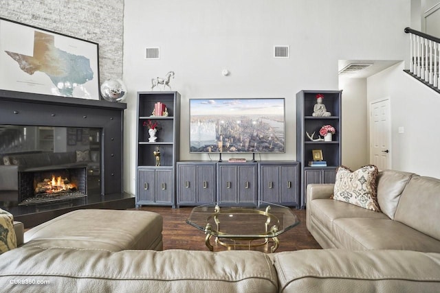 living room with dark wood-type flooring, a towering ceiling, and visible vents