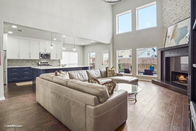 living room featuring a wealth of natural light, a fireplace, visible vents, and dark wood finished floors