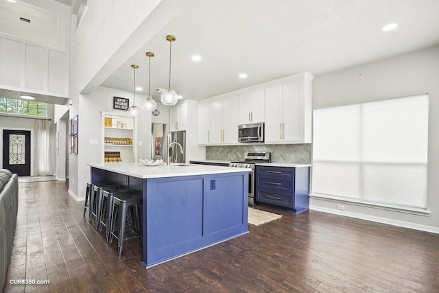 kitchen featuring dark wood-style flooring, light countertops, white cabinetry, stainless steel appliances, and decorative backsplash