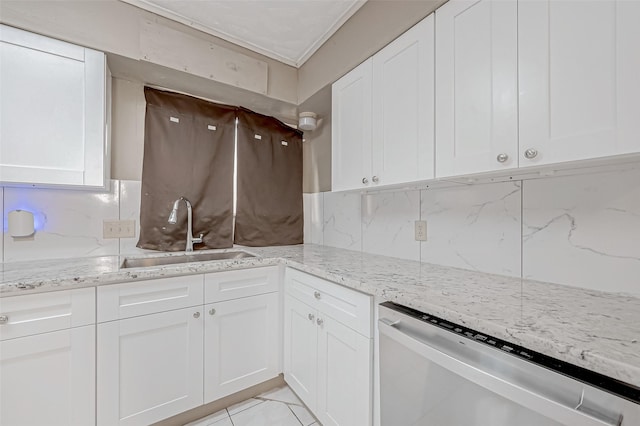 kitchen with stainless steel dishwasher, white cabinetry, backsplash, and a sink