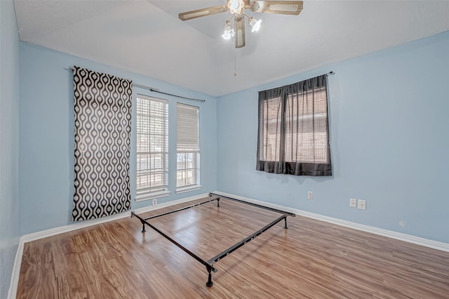 unfurnished room with a ceiling fan, baseboards, and wood finished floors