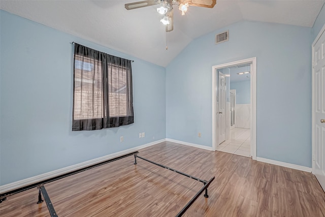 unfurnished bedroom featuring lofted ceiling, baseboards, ceiling fan, visible vents, and wood finished floors
