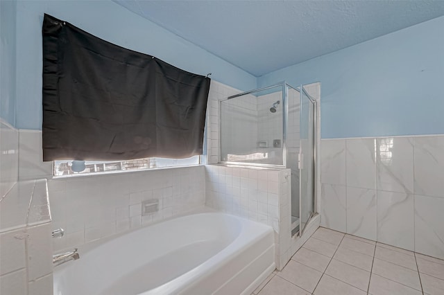 full bath featuring tile walls, tile patterned floors, a stall shower, a garden tub, and wainscoting