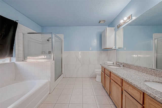 bathroom with tile walls, a textured ceiling, tile patterned floors, and a stall shower
