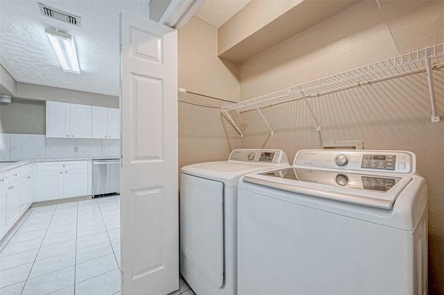 laundry room featuring light tile patterned floors, separate washer and dryer, a textured ceiling, visible vents, and laundry area