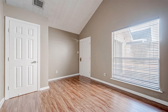 unfurnished bedroom with baseboards, lofted ceiling, visible vents, and light wood-type flooring