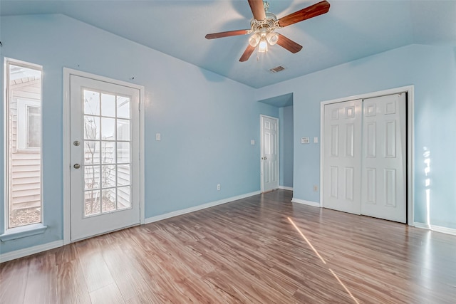 unfurnished bedroom featuring visible vents, baseboards, lofted ceiling, and wood finished floors