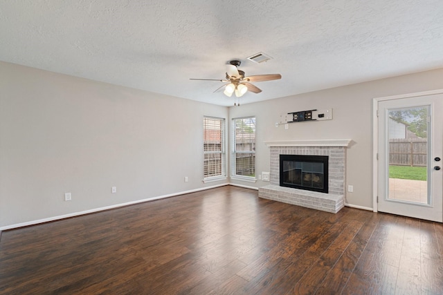 unfurnished living room with visible vents, baseboards, a brick fireplace, ceiling fan, and dark wood-type flooring