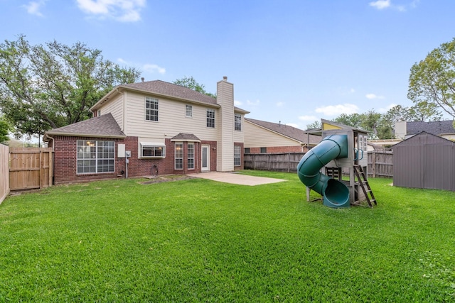 rear view of house featuring brick siding, a fenced backyard, a playground, and a lawn