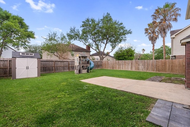 view of yard featuring an outdoor structure, a fenced backyard, a playground, and a storage unit