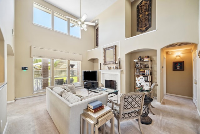 1314 Cross Valley Dr, Sugar Land, TX 77479 - living room featuring a towering ceiling, a tiled fireplace, light carpet, ceiling fan, and plenty of natural light