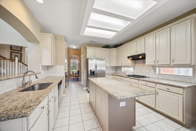 1314 Cross Valley Dr, Sugar Land, TX 77479 - kitchen featuring a sink, arched walkways, under cabinet range hood, tasteful backsplash, and a kitchen island
