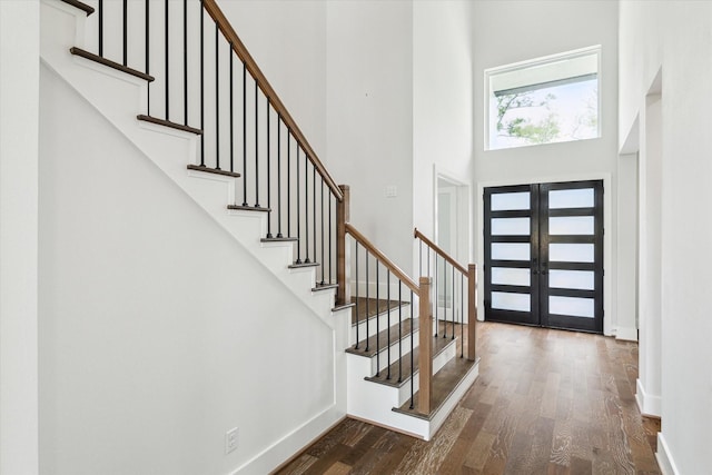 entryway with dark wood finished floors, a towering ceiling, french doors, baseboards, and stairs