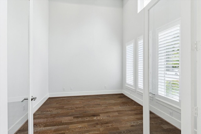 unfurnished room featuring dark wood-type flooring and baseboards