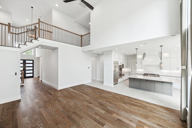 626 Attingham Dr, Houston, TX 77024 - unfurnished living room featuring light wood finished floors, a high ceiling, a ceiling fan, stairway, and baseboards
