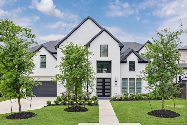 modern farmhouse style home featuring an attached garage, driveway, a front yard, and stucco siding