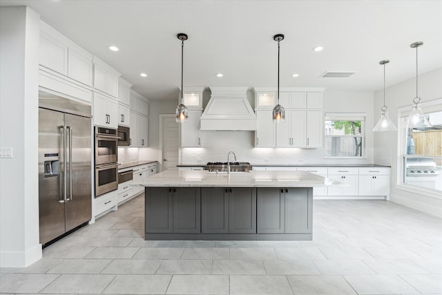 kitchen with white cabinets, backsplash, appliances with stainless steel finishes, and premium range hood