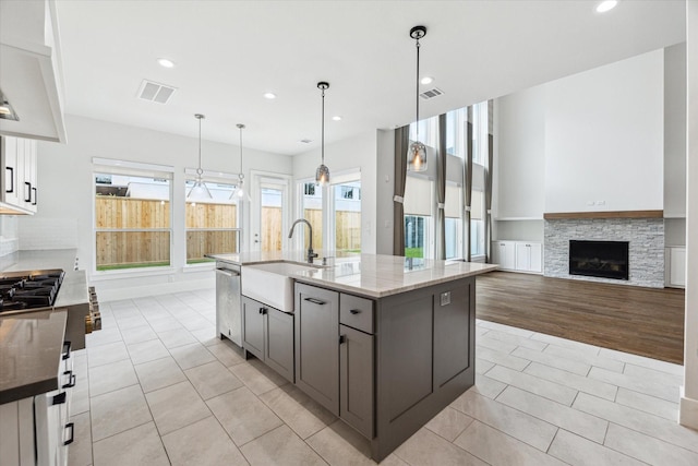 kitchen featuring light tile patterned flooring, visible vents, light stone counters, and a sink