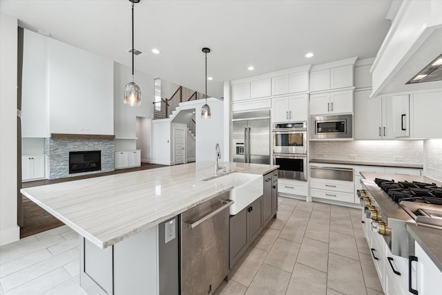 kitchen with a warming drawer, wall chimney exhaust hood, built in appliances, and light tile patterned floors
