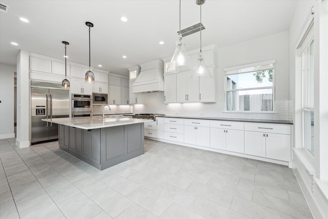 kitchen featuring a sink, tasteful backsplash, visible vents, custom exhaust hood, and built in appliances