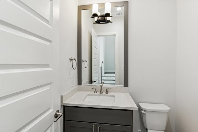 half bath with visible vents, vanity, and toilet