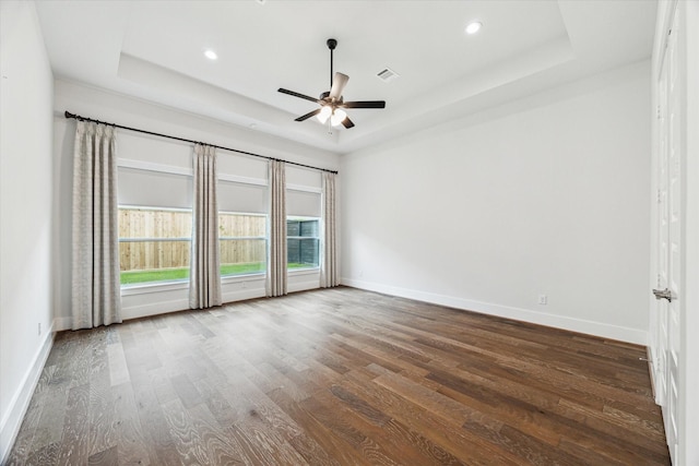 spare room with recessed lighting, a tray ceiling, wood finished floors, a ceiling fan, and baseboards