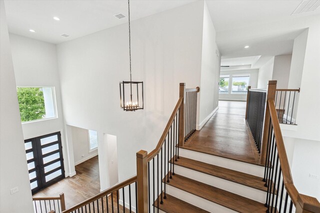 stairway featuring a chandelier, wood finished floors, and plenty of natural light