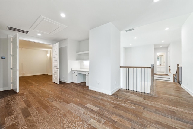 interior space with attic access, wood finished floors, visible vents, and built in study area