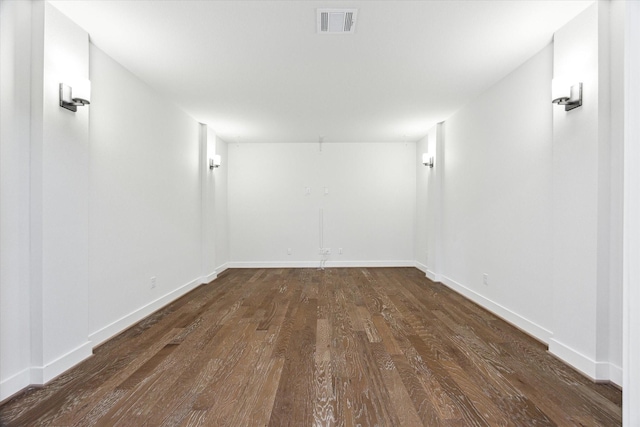 empty room with wood finished floors, visible vents, and baseboards