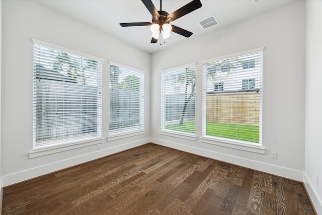 empty room featuring dark wood finished floors, ceiling fan, baseboards, and visible vents