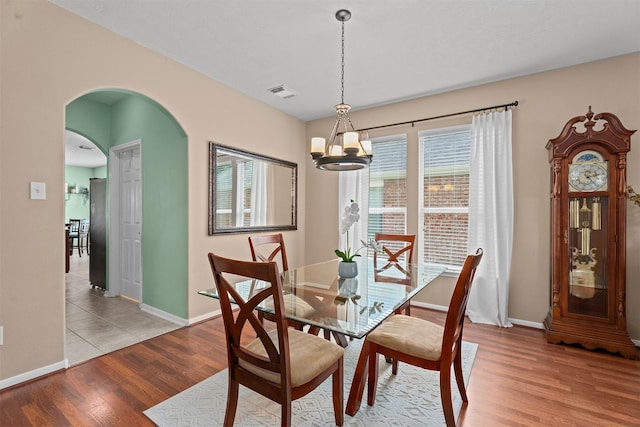 9330 Vander Rock Dr, Houston, TX 77095 - dining area with visible vents, arched walkways, an inviting chandelier, baseboards, and light wood finished floors