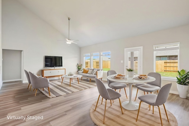 dining space with high vaulted ceiling, plenty of natural light, light wood-style flooring, and ceiling fan