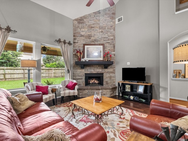 living area featuring high vaulted ceiling, a ceiling fan, a fireplace, wood finished floors, and visible vents