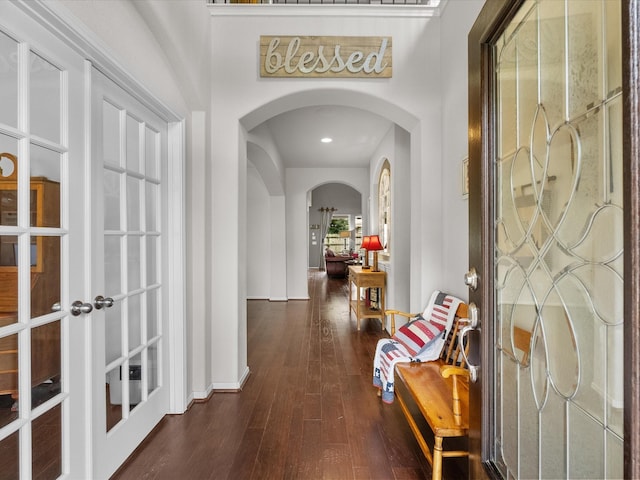 hallway featuring arched walkways, baseboards, french doors, and dark wood-type flooring