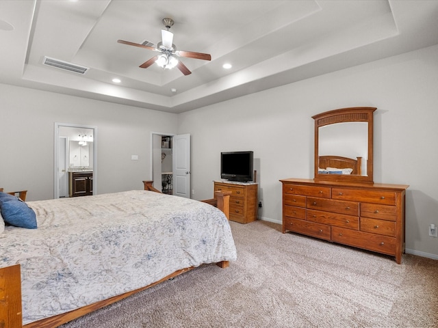 carpeted bedroom featuring ensuite bathroom, visible vents, baseboards, recessed lighting, and a tray ceiling
