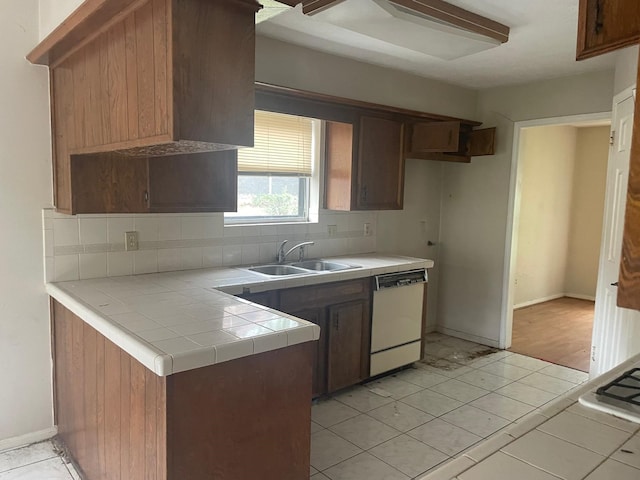 kitchen featuring tile counters, a sink, white dishwasher, backsplash, and light tile patterned floors