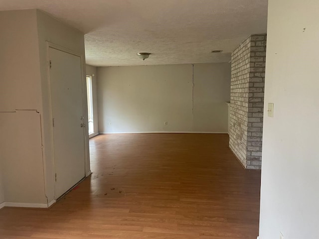 unfurnished room featuring baseboards, light wood finished floors, and a textured ceiling