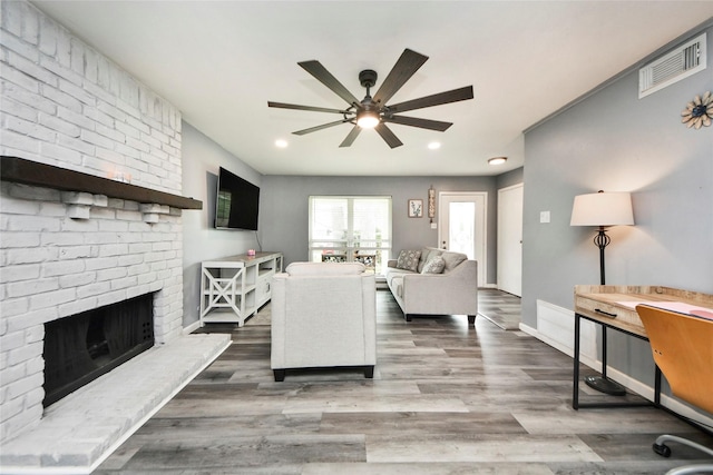 living area with a ceiling fan, wood finished floors, and visible vents